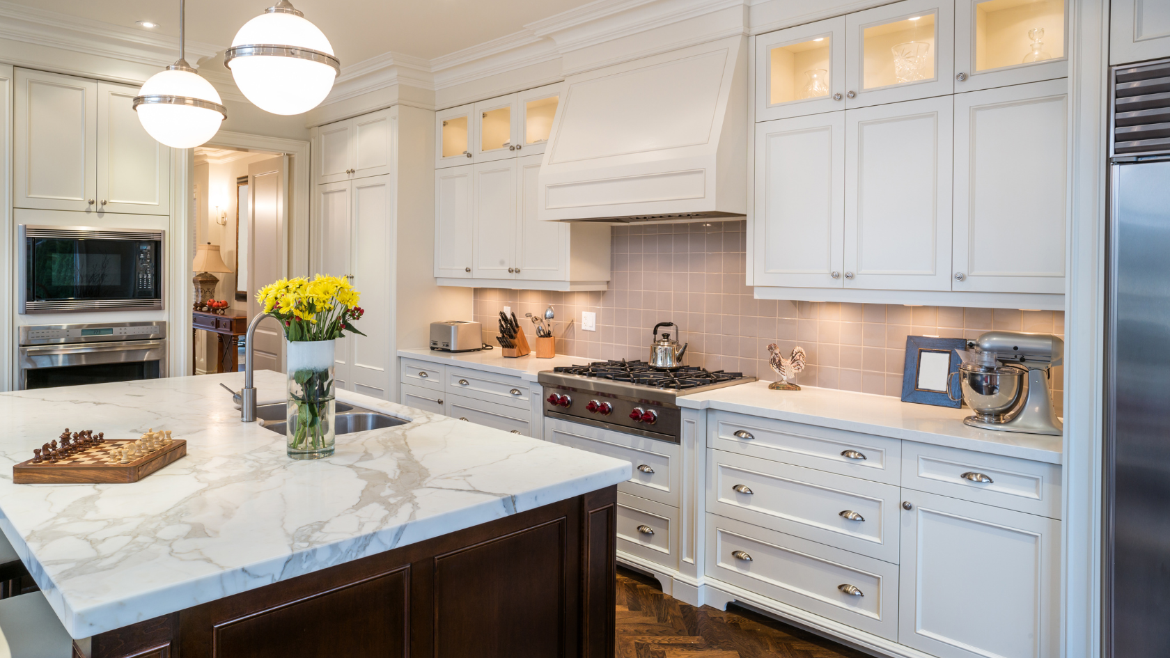 A kitchen with a marble counter top and white cabinets